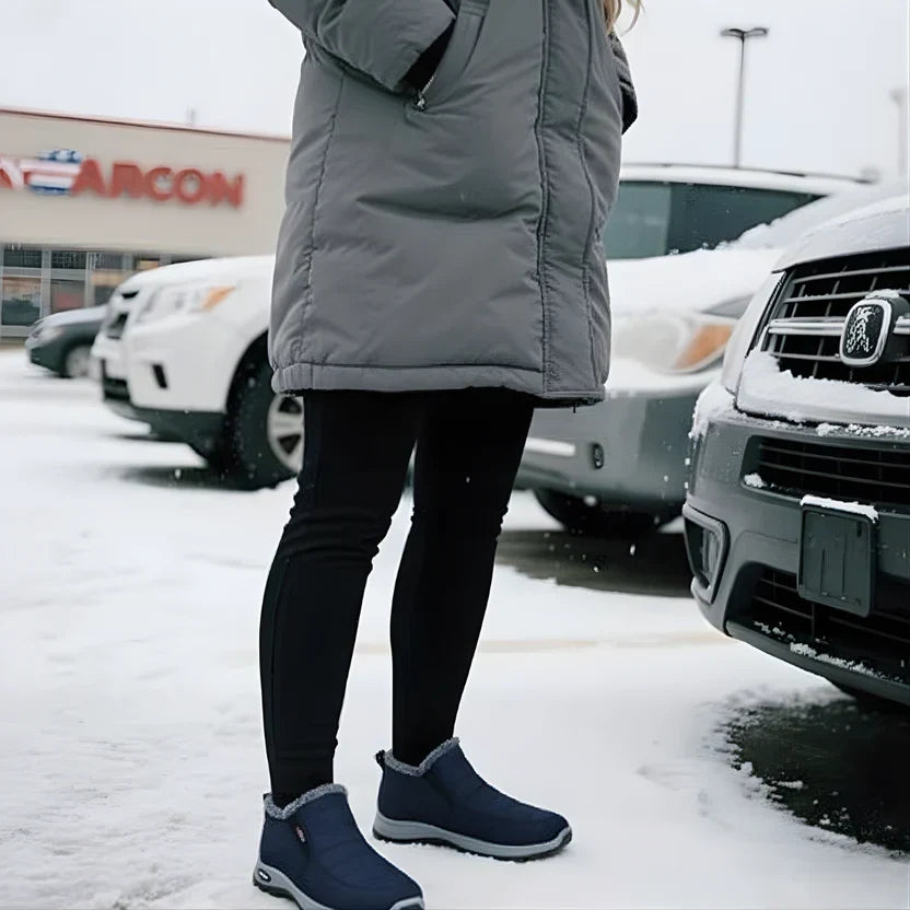 Woman wearing the Sianna boots in blue, standing in the snow beside a car